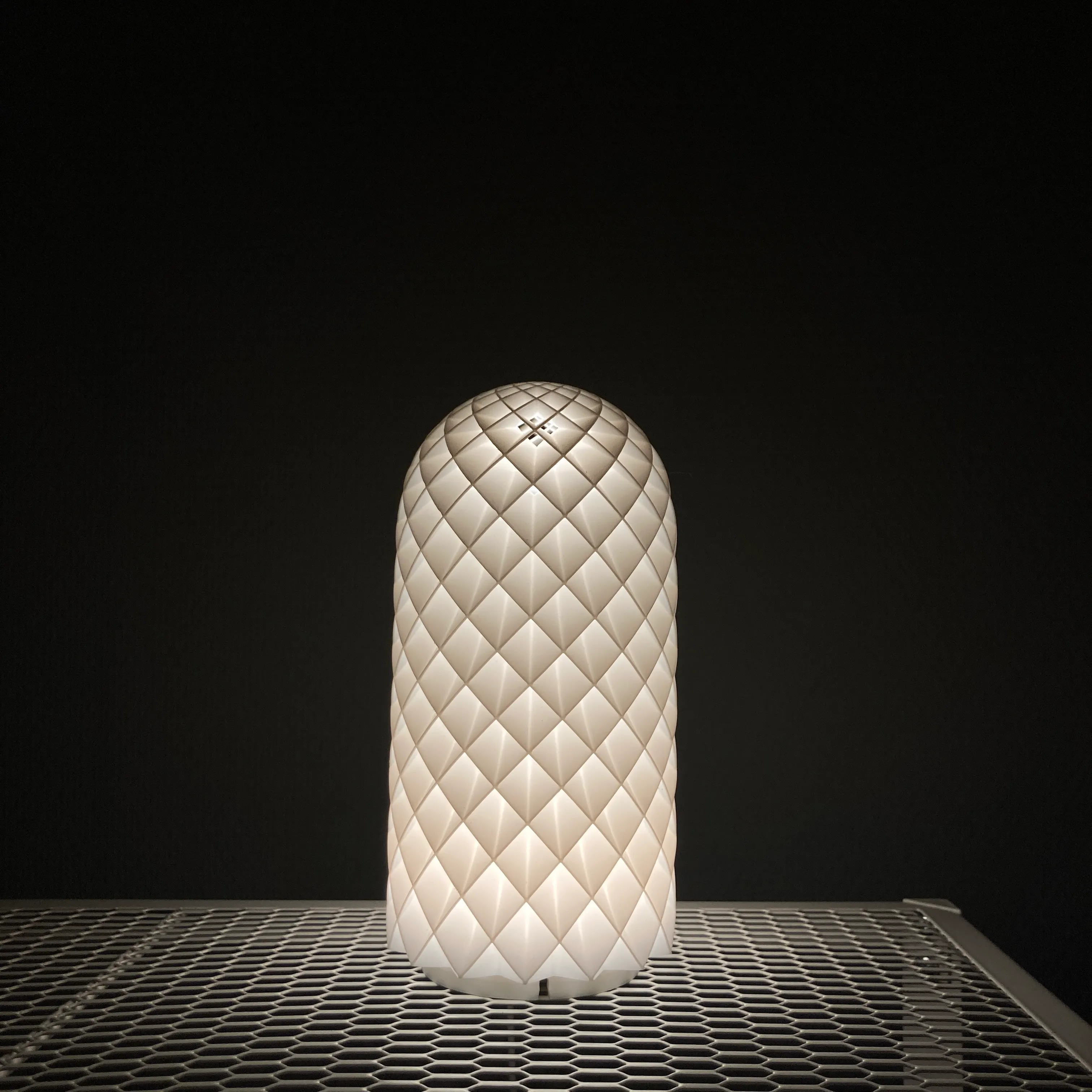 Lit white 3D printed table lamp with a diamond-pattern shade