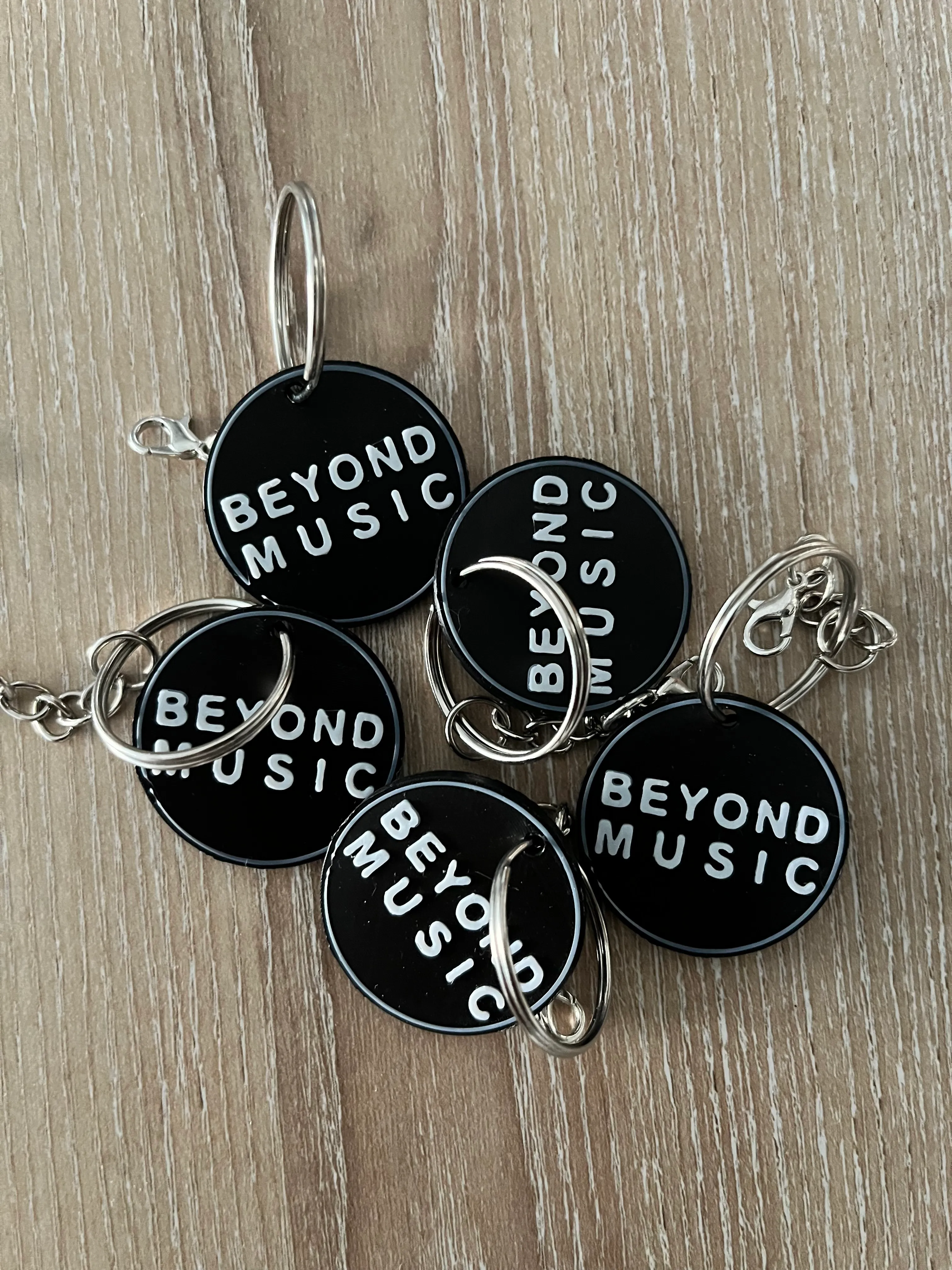 Round black-and-white 3D printed keychains with the Beyond Music logo