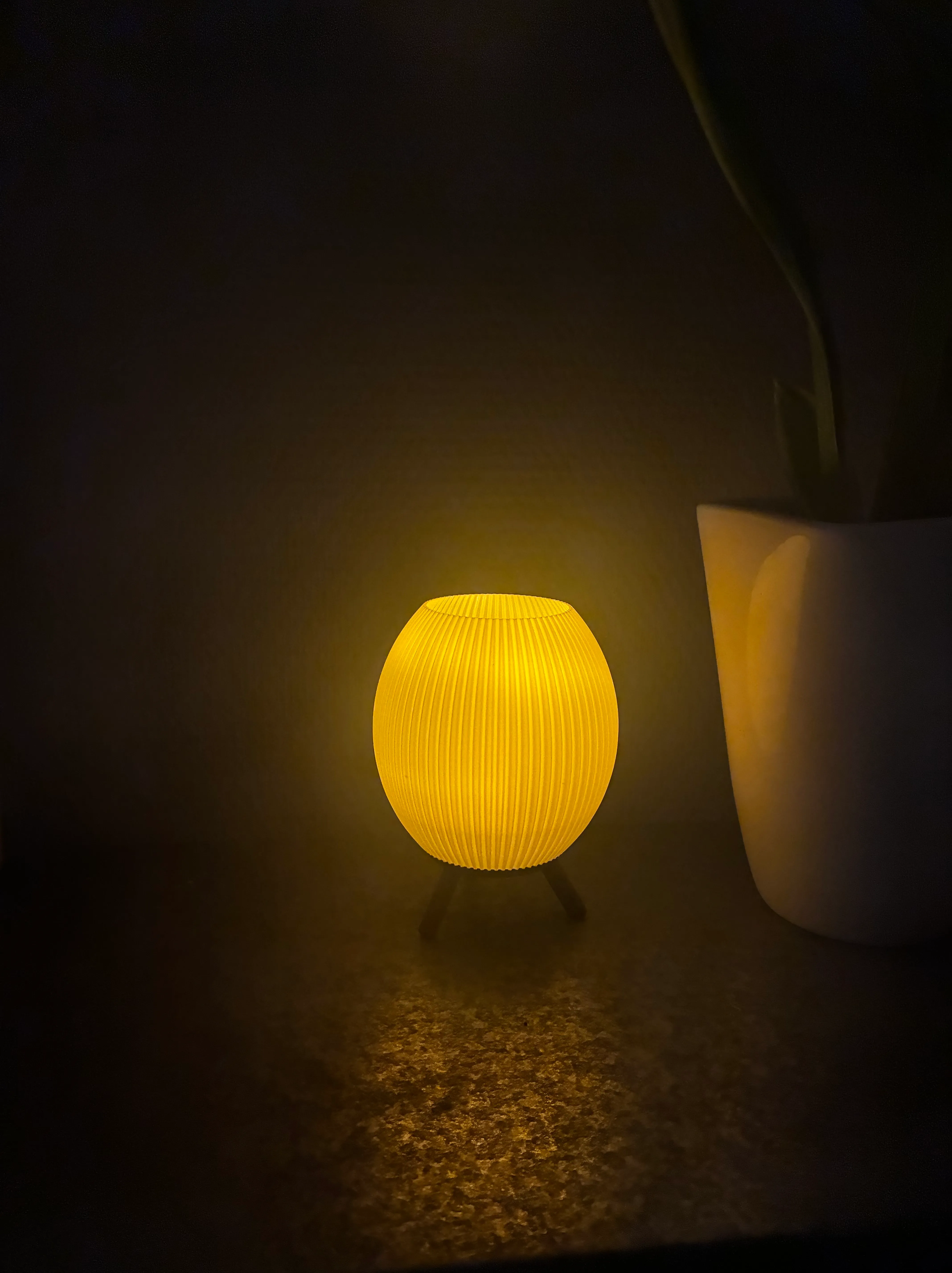 Round yellow 3D printed mini lamp glowing on a small tripod stand