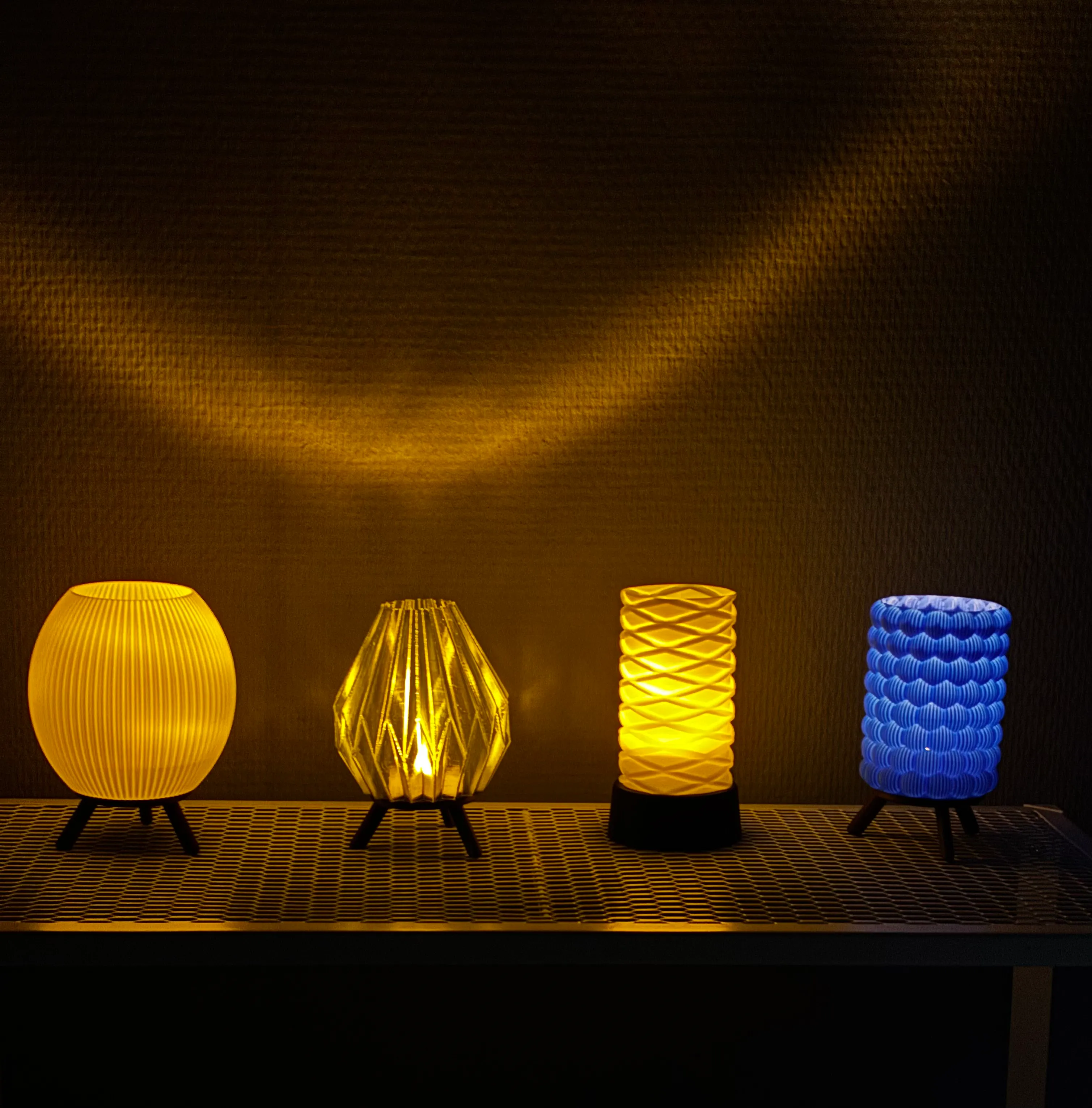 Four lit 3D printed mini lamps in yellow, gold and blue