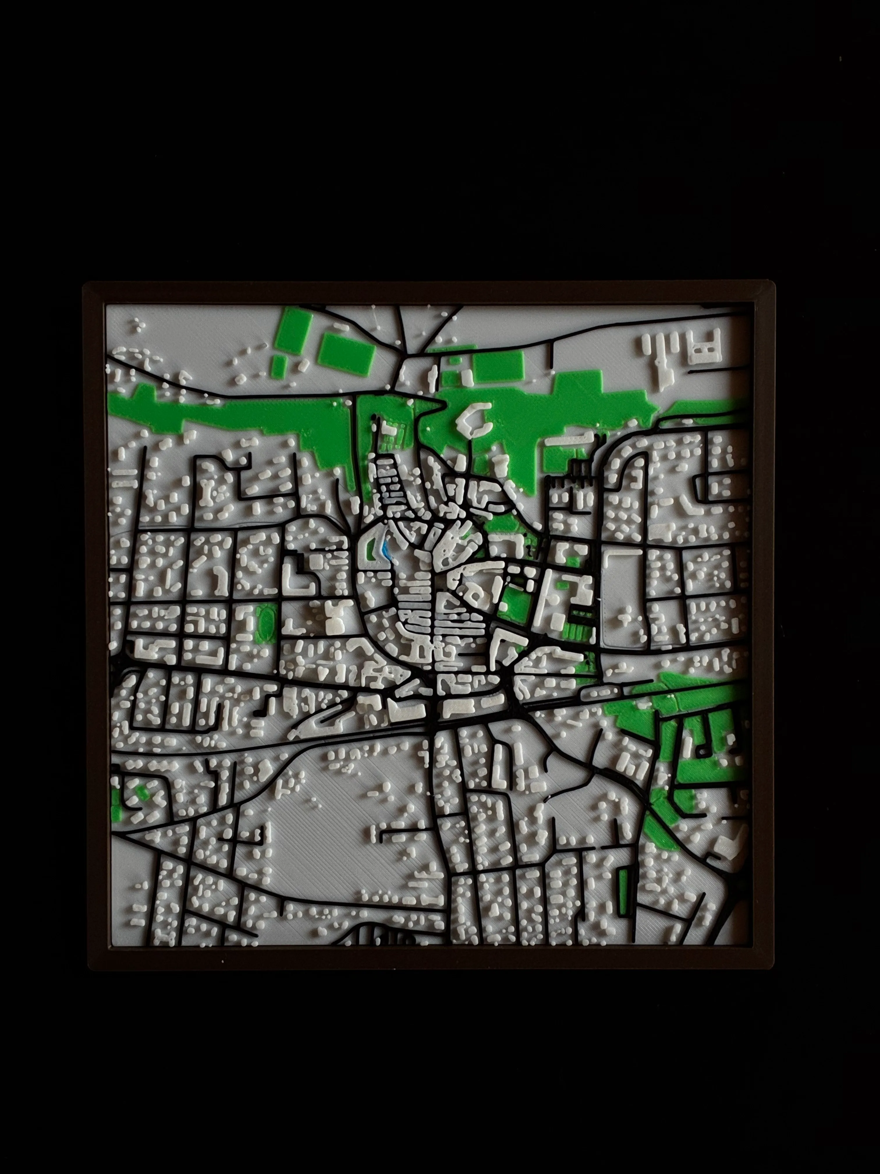 Multicolour 3D printed map of Spilimbergo with green areas and streets, in a dark frame